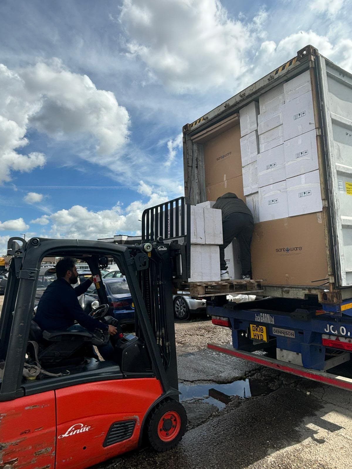 Nakliye konteynerinden vitrifiye ürün kutularını boşaltan forklift